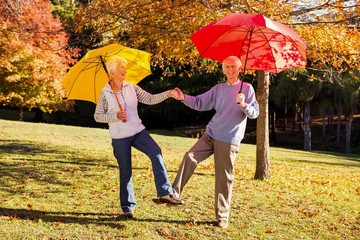 Senior couple dancing with umbrellas - Powered by Adobe