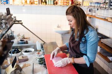 Side view of owner wrapping fresh fish in red paper at store