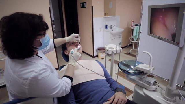 Dentist examining the mouth of a patient with an intraoral camera.