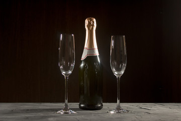 bottle of champagne and glasses over dark background