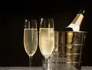 Champagne bottle in cooler and two champagne glasses.