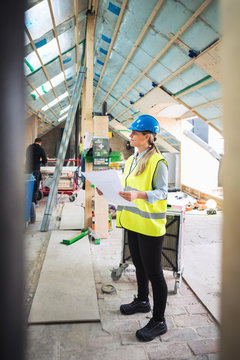 Confident female worker analyzing document while standing at construction site