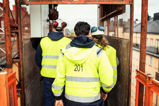 Rear view of construction workers standing in elevator at site