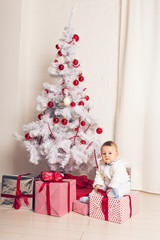 Cheerful little baby boy playing near the Christmas tree