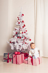 Cheerful little baby boy playing near the Christmas tree