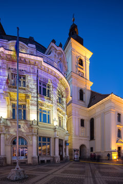 Twilight image of the City Hall and Holy Trinity Roman-Catholic church in Sibiu with architectural lights projecting Christmas images on the walls.