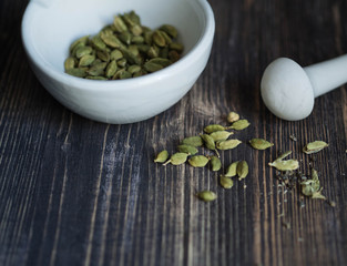 Cardamom in a mortar and scattered on the table
