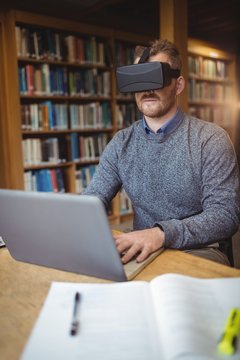 Mature student in virtual reality headset using laptop