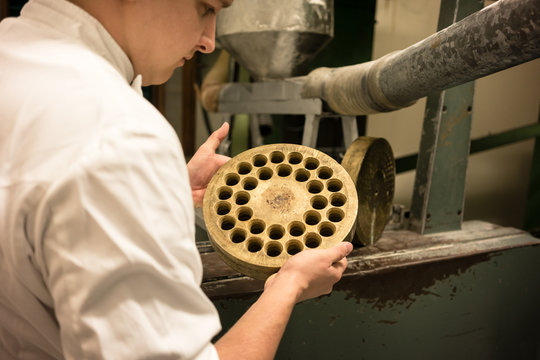 Chef in Italian pasta factory looking at discs the dough is bein