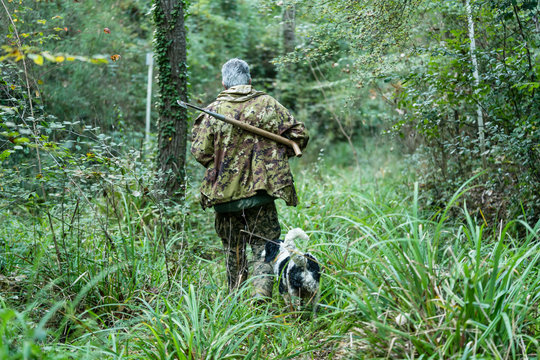Truffle hunter and his dog walking through the woods searching f