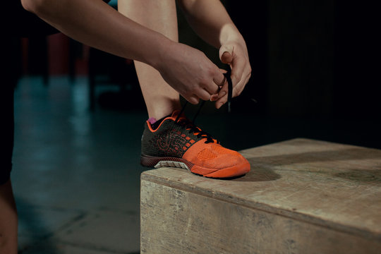 Young girl ties the laces on sneakers in the gym.