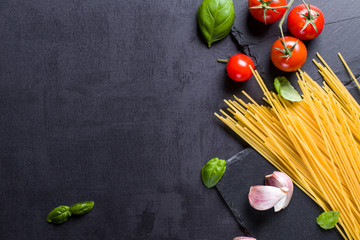 Food ingredients for Italian spaghetti on black stone slate background with much copy space of your...