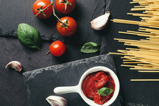 Food ingredients for Italian spaghetti on black stone slate background. Vegetarian version of pasta.