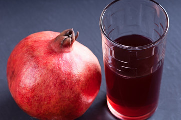 Pomegranate juice with pomegranate on a dark board