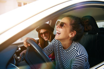 Laughing young woman driving a car - obrazy, fototapety, plakaty