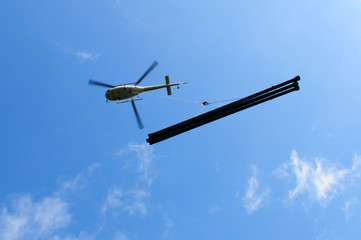 Fototapeta na wymiar Schweizer Alpen: Ein Transporthelikopter bringt Wasserleitungen ins Gebirge