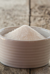 sugar in white bowlon wooden background