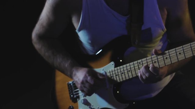 Guitarist plays heavy metal by electric guitar at the dark record studio