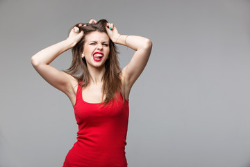 Young brunette woman showing devil horns hand gesture posing in studio.