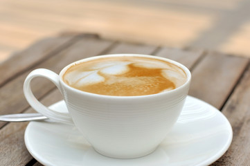 White cup of Latte coffee on wooden table.