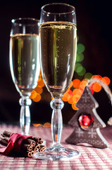 Two wineglasses of champagne and new year's decoration and cinnamon on the bokeh background