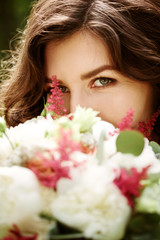 Naklejka premium Young beautiful woman close-up behind flowers