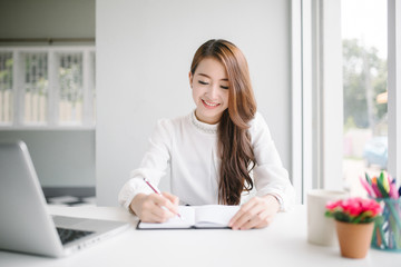 indoor picture of smiling Asia woman with notebook and pen