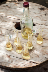Bottle of plum brandy with small glasses on wooden table