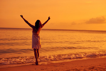 Fototapeta na wymiar Woman enjoying freedom on a sunset beach
