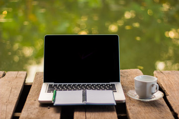 Laptop with coffee cup on the wood. background green