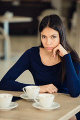Angry young woman with crossed arms at cafe