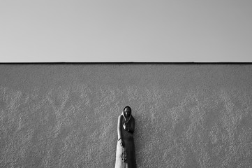 Statue of mourning woman, widow, in front of the wall. Minimalist composition in black and white