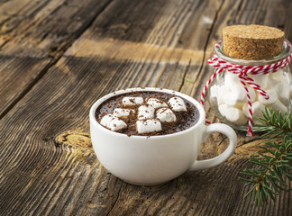 cup of fragrant homemade cocoa with marshmallows and crushed red white candy topping. On the simple wooden textural background. selective focus