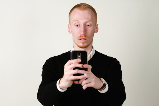 Businessman with mobile phone. Ginger  a successful man with a beard. Taking photo.