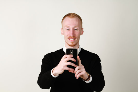 Businessman with mobile phone. Ginger  a successful man with a beard. Taking photo.