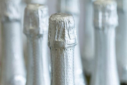 Silver champagne bottle necks and top caps at standing the light background in liquor store.