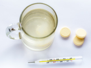 Thermometer readings of heat, and tablets effervescent aspirin dissolved in a cup of water.