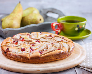 Cap of Tea and Homemade Pears Pie with Cranberry on the Wooden background