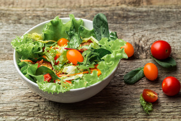 Salad with fresh vegetables - tomatoes, carrots, bell peppers and mixed greens - arugula, mesclun, mache.