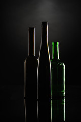 silhuettes of dark wine bottles on the black backgound contoured by the light