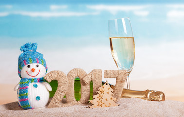Christmas 2017 inscription, champagne, snowman in the sand