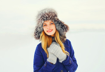 Winter fashion portrait happy smiling woman wearing a fur hat ov