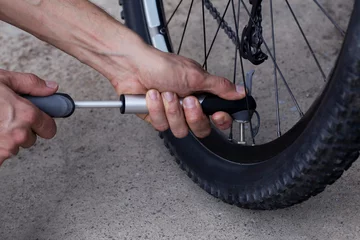 Tableaux ronds sur aluminium brossé Vélo The young man inflates bicycle wheel