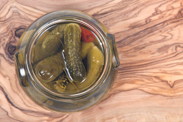 Natural organic dill cucumbers in jar on olive wood cutting board