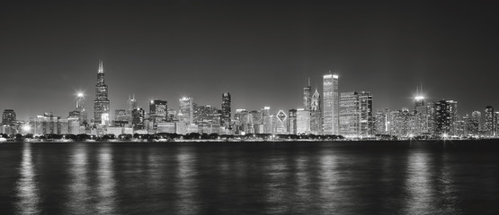 Fototapeta na wymiar Black and white panoramic picture of Chicago city skyline with reflection in Lake Michigan at night.