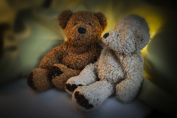 Two Teddy Bears, one is brown and the other white on green and yellow drapery