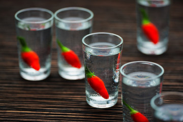 cold vodka with hot chili peppers , selective focus