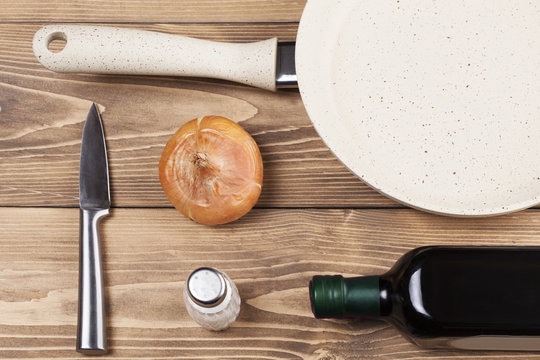 Cooking concept, frying pan and onions on wooden background