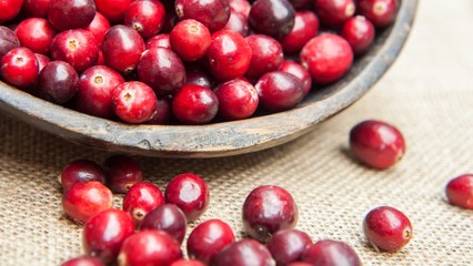 Fresh cranberries  in rustic wooden bowl on burlap Background an