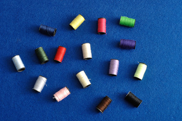 Spools sewing threads isolated on a blue background